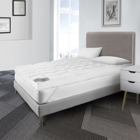 A white Royale 6cm mattress topper on a bed in a neatly furnished room with a grey headboard, white bedding, and side tables.