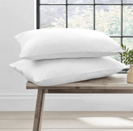 Two white duck feather pillows on a wooden bench with a window in the background.